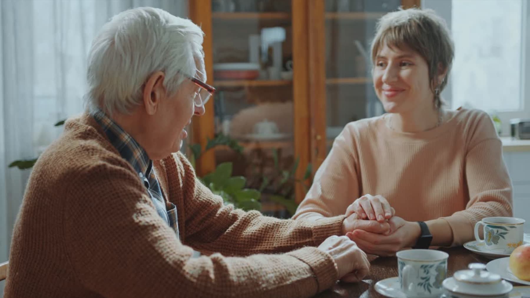 Caregiver holding hands with an older adult during funeral planning support